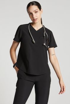 MADE FOR THE WAY YOU MOVE™: A classic short sleeve scrub top you will wear over and over again, in buttery-soft lightweight, stretchy fabric. The flattering shirt tail hem with a classic fit and room for layering when you want a bit more coverage. A badge tab, well-placed functional pockets, reflective branding for safety and a water-repellent treatment to get you through your shift. These scrubs are breathable, wash up like new and customers rave over the flattering fit. Bonus: They are made wi Slim Suit Pants, Wrap Tunic, Womens Golf Shirts, Women's Uniforms, Slim Suit, Cropped Linen Pants, Womens Scrubs, Sustainable Fabrics, Scrub Tops