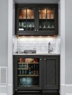 an open cabinet in the corner of a kitchen with wine glasses and bottles on it