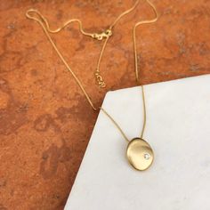 14KT Yellow Gold Matte, Textured, Abstract Round Pendant Charm with Off-Center Diamond. Modern + contemporary piece- perfect for everyday wear and/or layering! Adjustable 16~18" length 1mm wheat chain Pendant measures: 15mm x 12mm Solid 14K 14K lobster clasp Weight: 3.00 grams (1) genuine, .06 carat diamond Solid gold Modern Diamond Necklace With Adjustable Chain, Modern Oval Necklace For Anniversary, Modern Diamond Necklace With Cable Chain, Modern Tarnish Resistant Oval Pendant Necklace, Modern Polished Chain Necklace As Gift, Modern Polished Chain Necklace For Gift, Modern Oval Pendant Necklace For Everyday, Modern Yellow Gold Diamond Necklace For Everyday, Modern Diamond Necklace With Adjustable Chain For Everyday