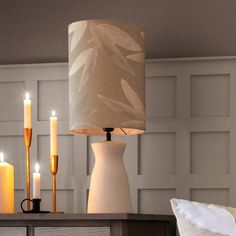 a lamp that is sitting on top of a table next to a vase and candles