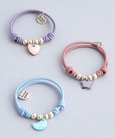 three different colored bracelets with charms and hearts on them, one is pink, the other is blue