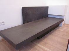 a concrete bench sitting on top of a hard wood floor next to a white wall