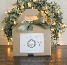 a small box with a green ribbon on it sitting on top of a wooden table