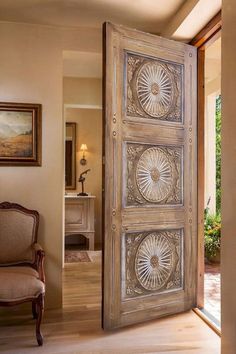 an open door leading to a living room with a chair and painting on the wall