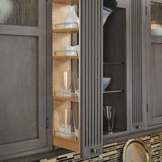 an open cabinet in a kitchen filled with dishes and glasses