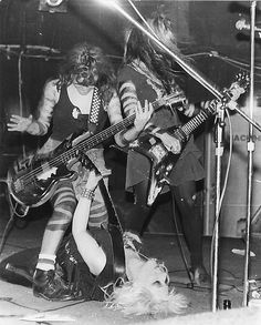 an old black and white photo of some people playing guitars on stage with a dog in the foreground