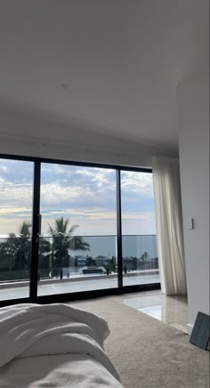 an empty bedroom with large windows overlooking the ocean