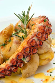 an octopus stuffed potato dish on a white plate with lemons and rosemary garnish