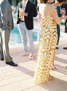 a group of people standing next to each other near a pool with drinks in their hands