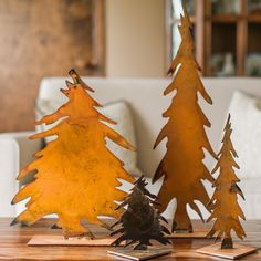 three metal trees sitting on top of a wooden table in front of a white couch