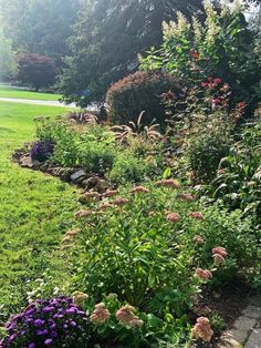 a garden filled with lots of flowers and greenery next to a lush green field