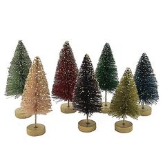 small christmas trees are lined up in different colors and sizes, with gold base bases