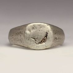 This handmade signet ring has a little 1.2mm Champagne diamond bead set for a subtle sparkle. The face is 10x10mm with a tapering shank for comfort.  Made by casting recycled sterling silver in beach sand, it has a lovely chunky feel. The sand mould creates the texture you can see on the ring. The ring pictured is a size M. Your ring will be made to order and each one comes out differently.  The rustic and irregular nature of our sandcast range comes from Justin's own technique; as the name suggests each ring is cast in beach sand. With a different mould used each time, every ring is totally unique - make it that little bit more special by sending us your own beach sand.   You can buy the mould the ring is cast in if you like. If you would like to use some of your own metal or sand please Minimalist Hand Forged Signet Ring For Anniversary, Minimalist Hammered Signet Ring As Gift, Minimalist Hand Forged Engraved Promise Ring, Hand Forged Round Signet Ring For Anniversary, Hand Forged Sterling Silver Signet Ring For Anniversary, Minimalist Sterling Silver Rings With Lost Wax Casting, Minimalist Silver Hand Forged Engraved Ring, Minimalist Silver Engraved Ring Hand Forged, Minimalist Hand Forged Sterling Silver Engraved Ring