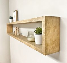 a wooden shelf with two jars and a succulent in it on the wall