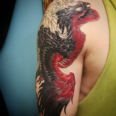 a woman with a tattoo on her arm has a large black and red dragon tattooed on it's shoulder