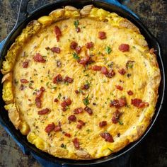 an omelet in a cast iron skillet with bacon and cheese on top