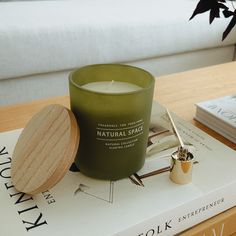 a green candle sitting on top of a table next to a book and a pen