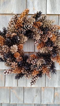 a wreath made out of pine cones sitting on top of a brick wall