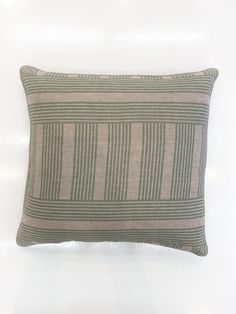 a gray and green striped pillow sitting on top of a white wall