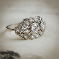 an antique diamond ring is shown on a white tablecloth, with the center stone surrounded by smaller round diamonds