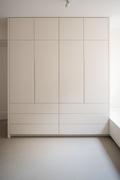 an empty room with white cupboards and a ceiling fan