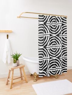 a white bath tub sitting next to a wooden stool in front of a black and white shower curtain