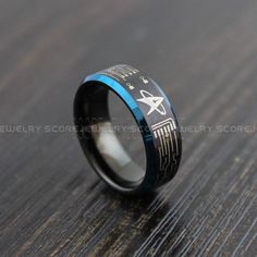 a black and blue ring with an etched design on the inside, sitting on a wooden surface