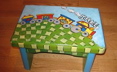 a child's wooden toy train table with green grass and yellow squares on it