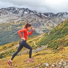 a woman running up a hill in the mountains