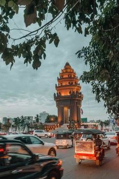 cars driving down the road in front of a tall tower