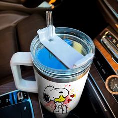 a cup with a spoon sticking out of it sitting on top of a car dash board