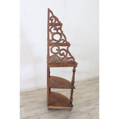 an ornate wooden shelf with two shelves on each side and one shelf holding a book