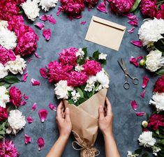 someone holding a bouquet of flowers in front of pink and white peonies on a table