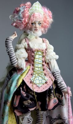 a close up of a doll wearing a dress and hat with pink hair on it