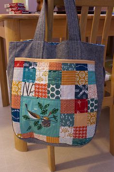 a tote bag sitting on top of a wooden chair in front of a table