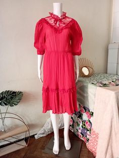 Cute True Vintage prairie dress from the early 1980s. Structured semi sheer light fabric in a beautiful tone of coral red. High neck with lace and satin tie band. More lace and satin details on the bib. Half long puff sleeves, elasticated cuffs. Elasticated waist. Wide skirt with ruffle hem. Lined skirt. Made in France! BRAND: No brand label anymore ERA: 1980s COLOR: Coral red  Fabric: 67% polyester, 33% cotton; lining 100% polyamide SIZE: Vintage size FR44, runs smaller and  fits best size S-M Vintage Prairie Dress, Wide Skirt, Brand Label, Prairie Dress, Coral Red, Red High, Color Coral, Lined Skirt, Puffed Sleeves Dress