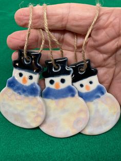 three ceramic snowmen hanging from twine strings