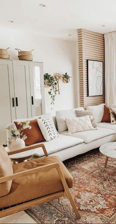 a living room filled with lots of white furniture and decor on top of a rug