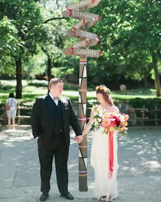 a man and woman standing next to each other near a pole with street signs on it