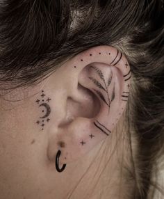 a woman's ear with an arrow and stars tattoo on her left behind the ear