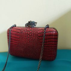 The Marley Bag from House Of Harlow. This convertible clutch is croc grain, in dark cinnabar red. Hinged boxy bag has a 44 inch long chain handle. The bronze jaguar clasp is Deco inspired, with glittering emerald eyes. Lining is textured black grosgrain, accented with a small slip pocket. Statement event bag. Labeled "House Of Harlow 1960". To convert to clutch, stow the chain handle inside the purse. VINTAGE 1980's.  Width: 5-3/4" Height: 3-3/4" Depth: 2" Luxury Red Clutch Box Bag, Red Formal Shoulder Bag Rectangular Case, Red Rectangular Evening Bag With Chain Strap, Luxury Red Box Bag For Evening, Red Clutch Evening Bag, Red Clutch Box Bag For Formal Occasions, Red Rectangular Box Bag For Formal Occasions, Red Rectangular Box Bag, Chic Red Rectangular Box Bag