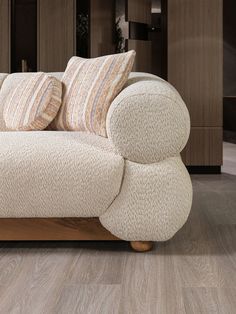 a white couch with two pillows on top of it in a living room next to a wooden floor