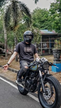 a man riding on the back of a motorcycle down a street next to palm trees