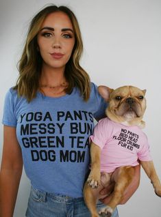 a woman holding a small dog wearing a yoga t - shirt that says yoga pants messy bun green tea dog mom