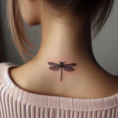 a woman's back neck with a small dragonfly tattoo on her left side