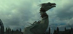 a dragon statue in front of a cloudy sky