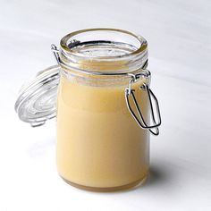 a jar filled with yellow liquid sitting on top of a white counter next to a glass container