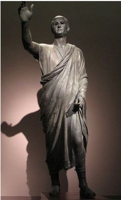 a statue of a man with his hand up in the air and wearing a robe