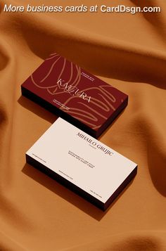 two business cards sitting on top of a bed covered in brown fabric with the words, more business cards at card design com