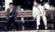 two men in suits sitting on a wooden bench